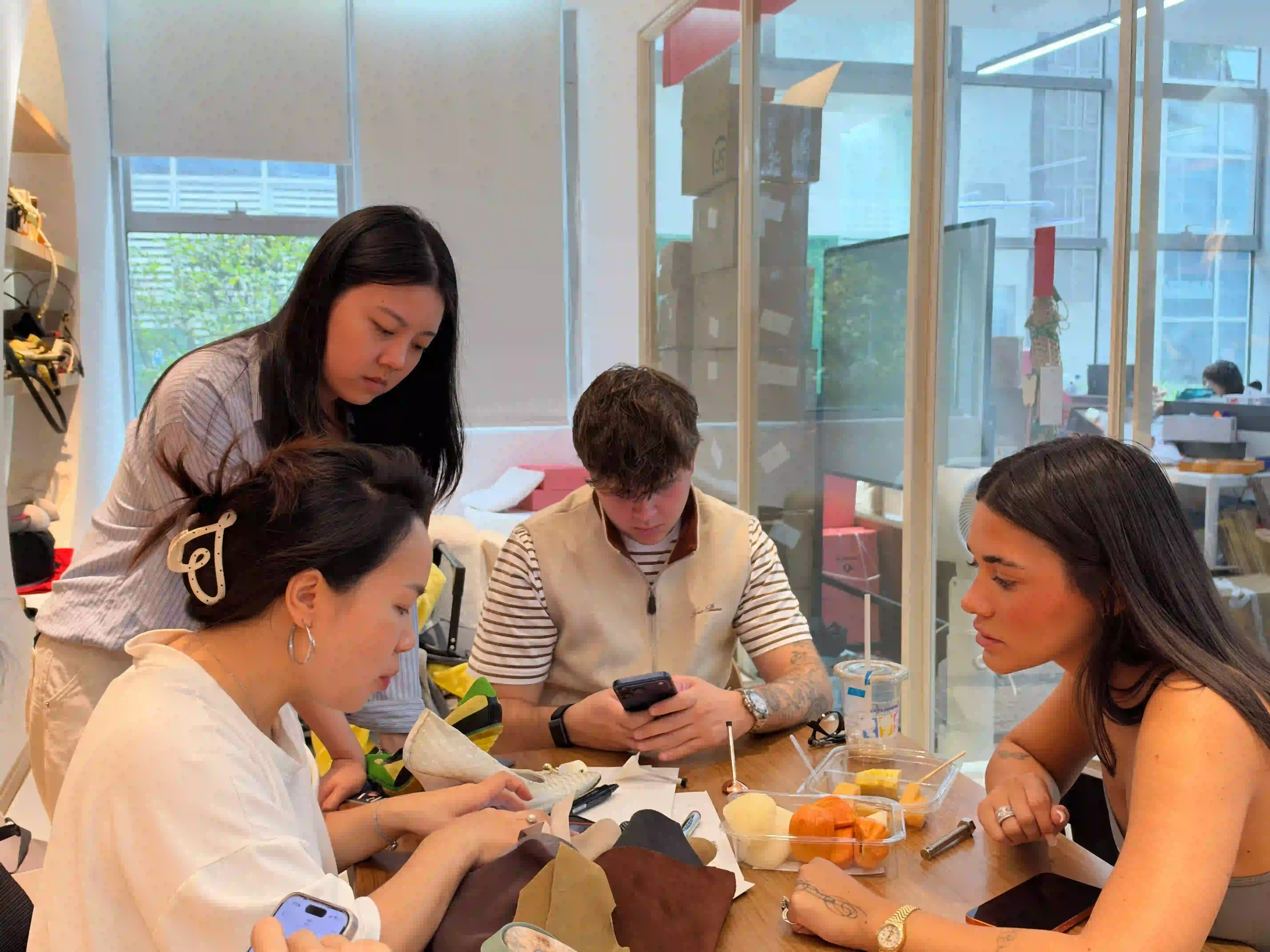 Four people around a table in a sample room, client and design team looking through brown, olive and blue-grey leather swatches